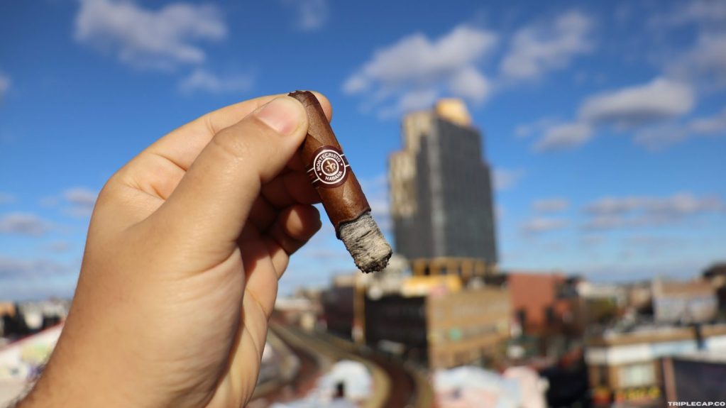 A hand holding a Montecristo Especiales No.2 cigar against a backdrop of a blue sky with scattered clouds and city buildings.

Montecristo Especiales No.2 Conclusions