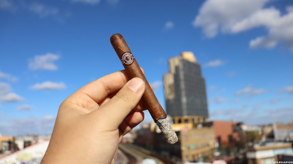 A person holding a Montecristo Especiales No.2 cigar with a city skyline and blue sky in the background.

Montecristo Especiales No.2 Second Third